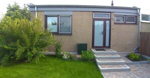 Stunning home with a modern design, featuring a glass front door and a beautifully manicured garden.