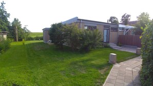 A modern house with a well-maintained lawn and a small garden area. - Chic bungalow (renovated in 2018) directly on the dike to the IJsselmeer / beach (Lemmer)