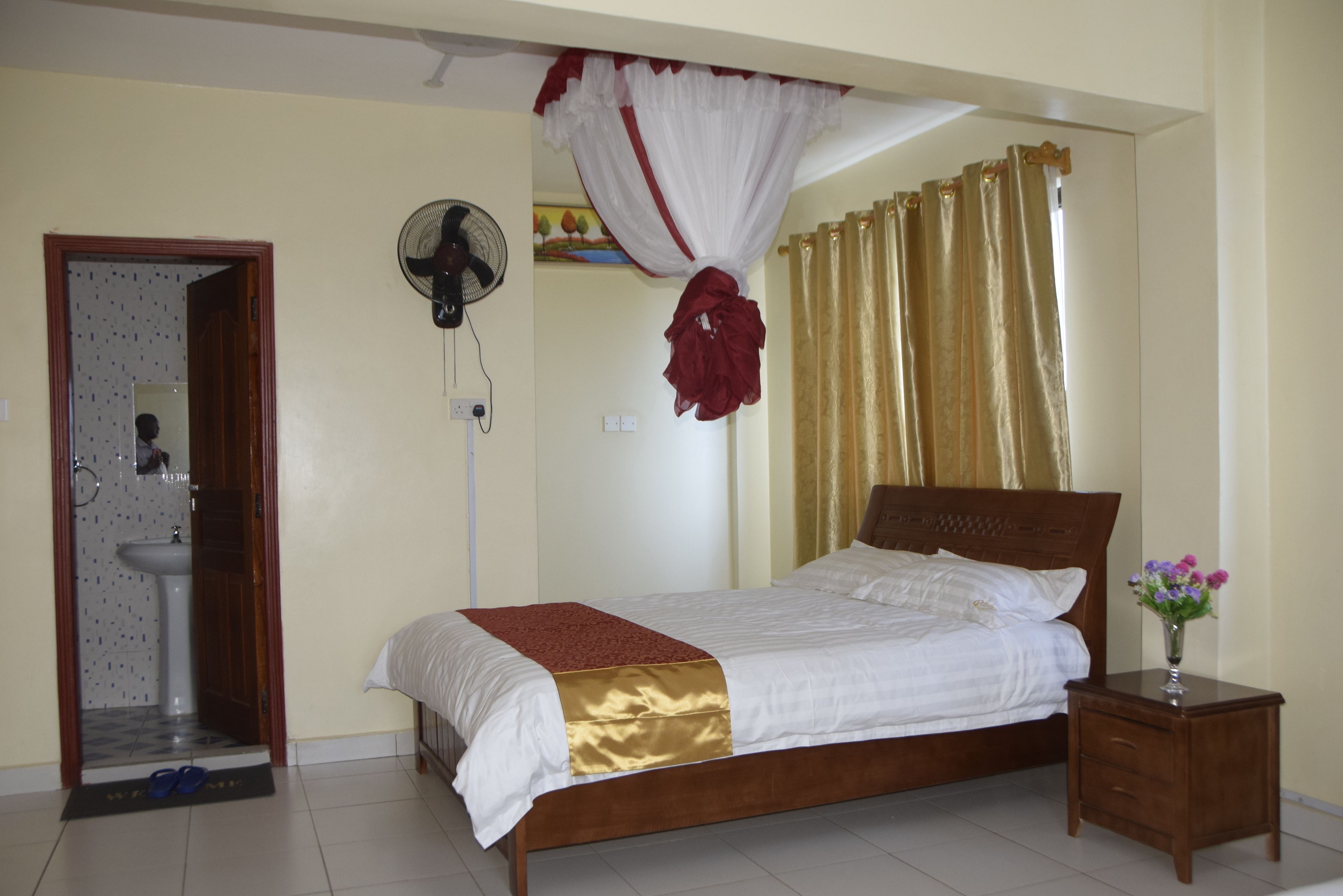 A bedroom with a bed, bedside table, and a fan.