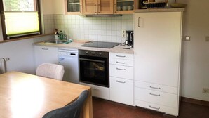 Une cuisine compacte équipée d’un lave-vaisselle, d’un four et d’une machine à café.