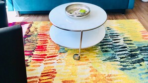 Un canapé de couleur turquoise, une table basse blanche et un tapis coloré dans un coin salon.