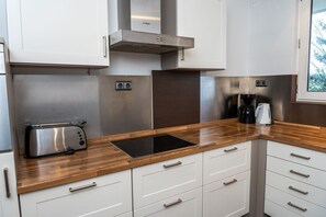A modern kitchen with white cabinets, stainless steel appliances, and a wooden countertop.