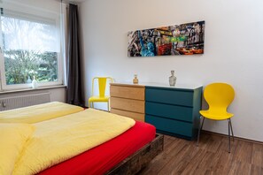A bedroom with a bed, a dresser, a chair, and a window with curtains.