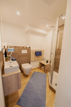 Une salle de bain moderne avec une douche, des toilettes, un lavabo et un tapis bleu.