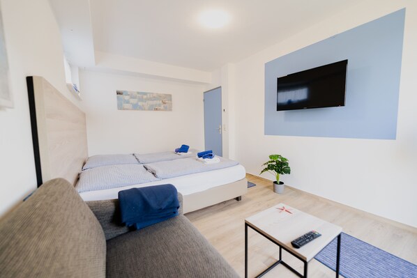 Une chambre d’hôtel moderne équipée d’un lit, d’un canapé, d’une télévision et d’une petite table.