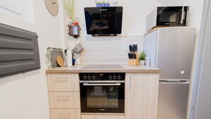 A compact kitchen with a built-in oven, microwave, and refrigerator. - Holiday house Beautiful view Fischerstube "Blau" (Hemfurth-Edersee)