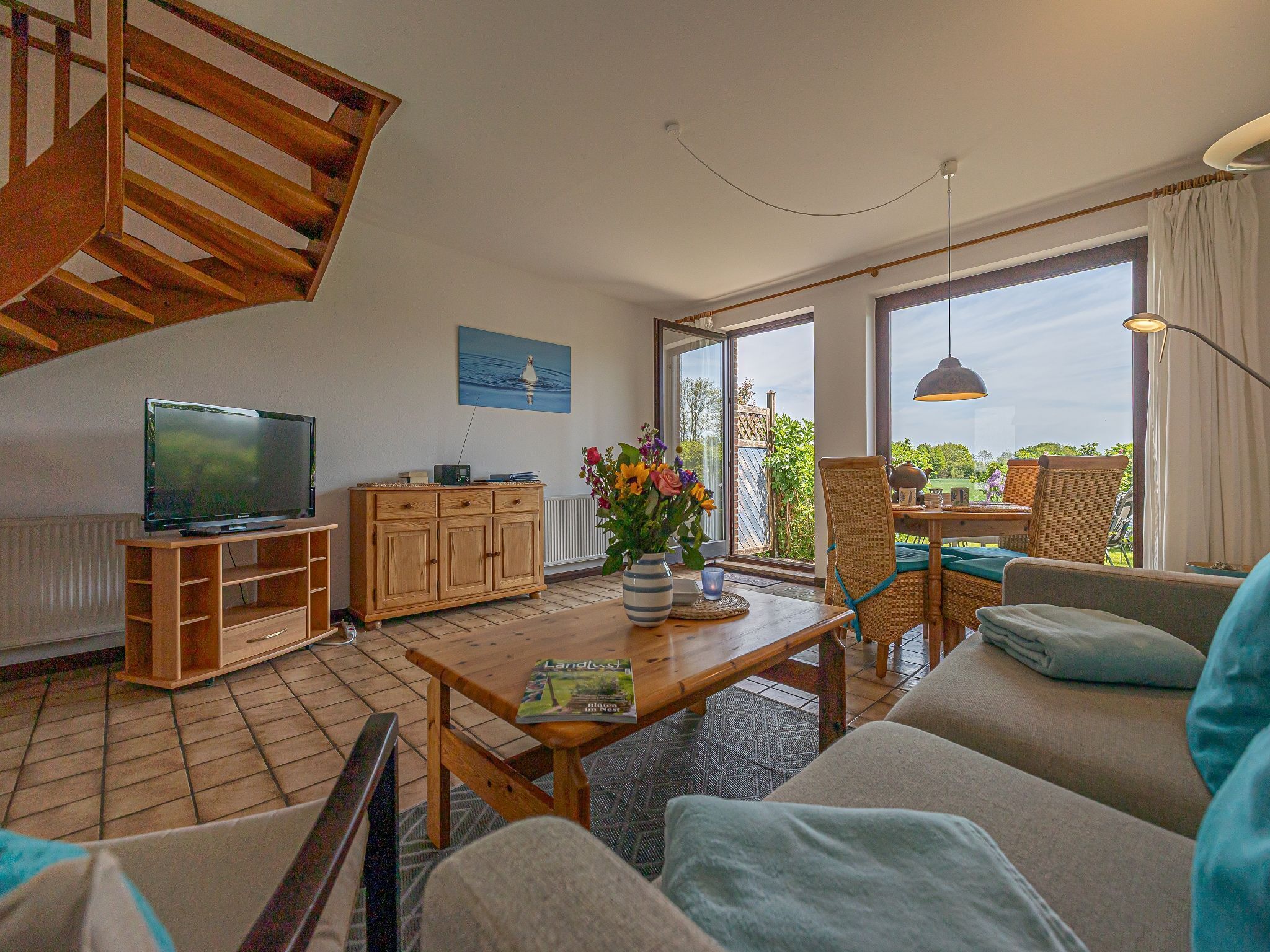 A living room with a TV, wooden cabinet, sofa, and a table with a magazine.