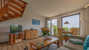 A living room with a TV, wooden cabinet, sofa, and a table with a magazine.