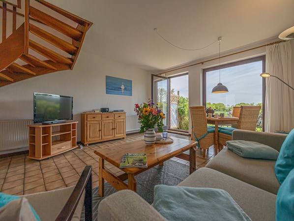 A living room with a TV, wooden cabinet, sofa, and a table with a magazine.