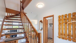 A wooden staircase with a handrail, a kitchen area with a microwave, and a wooden wall-mounted hanger rack.