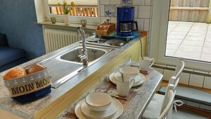 Une cuisine équipée d’un évier, d’une machine à café et d’un panier de pain.
