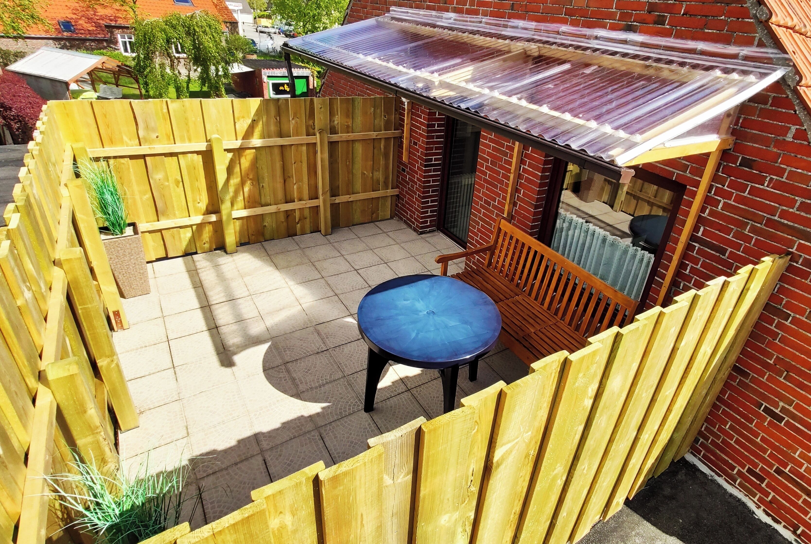 A patio area with a wooden fence, a table, and a covered seating area.