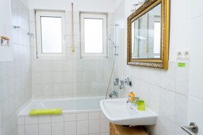 Een bad/douchecombinatie, een haardroger, handdoeken, zeep