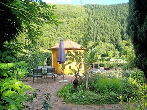 A rustic wooden cabin with a patio area featuring outdoor furniture and a bird sculpture. - Apartment with balcony (4 stars, DTV-Classified) (Traben-Trarbach)