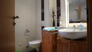 A bathroom with a toilet, sink, mirror, and wooden cabinets.