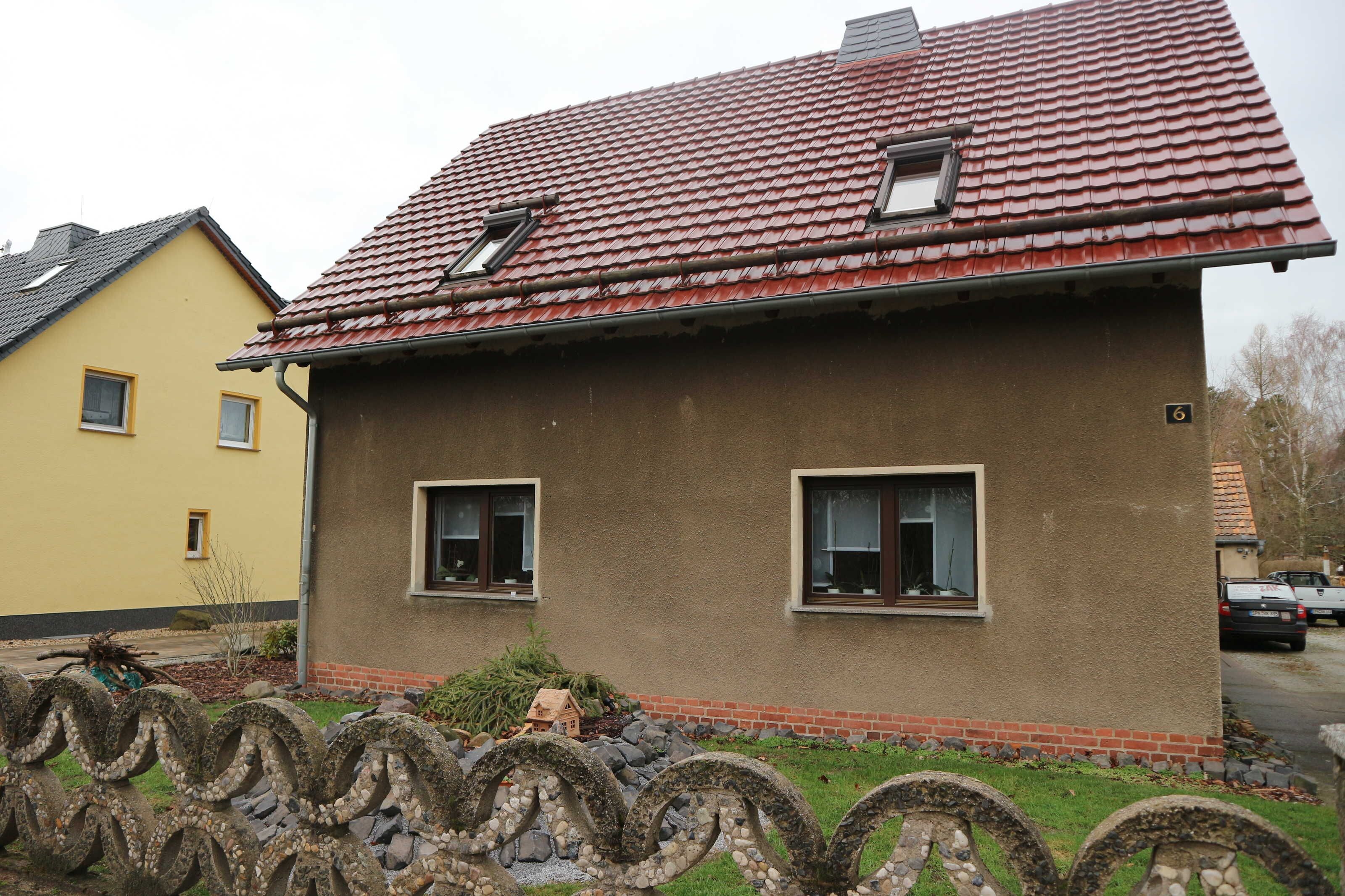 A house with a red-tiled roof, two windows, and a small porch area.