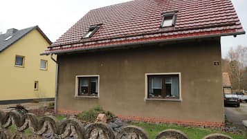 A house with a red-tiled roof, two windows, and a small porch area.