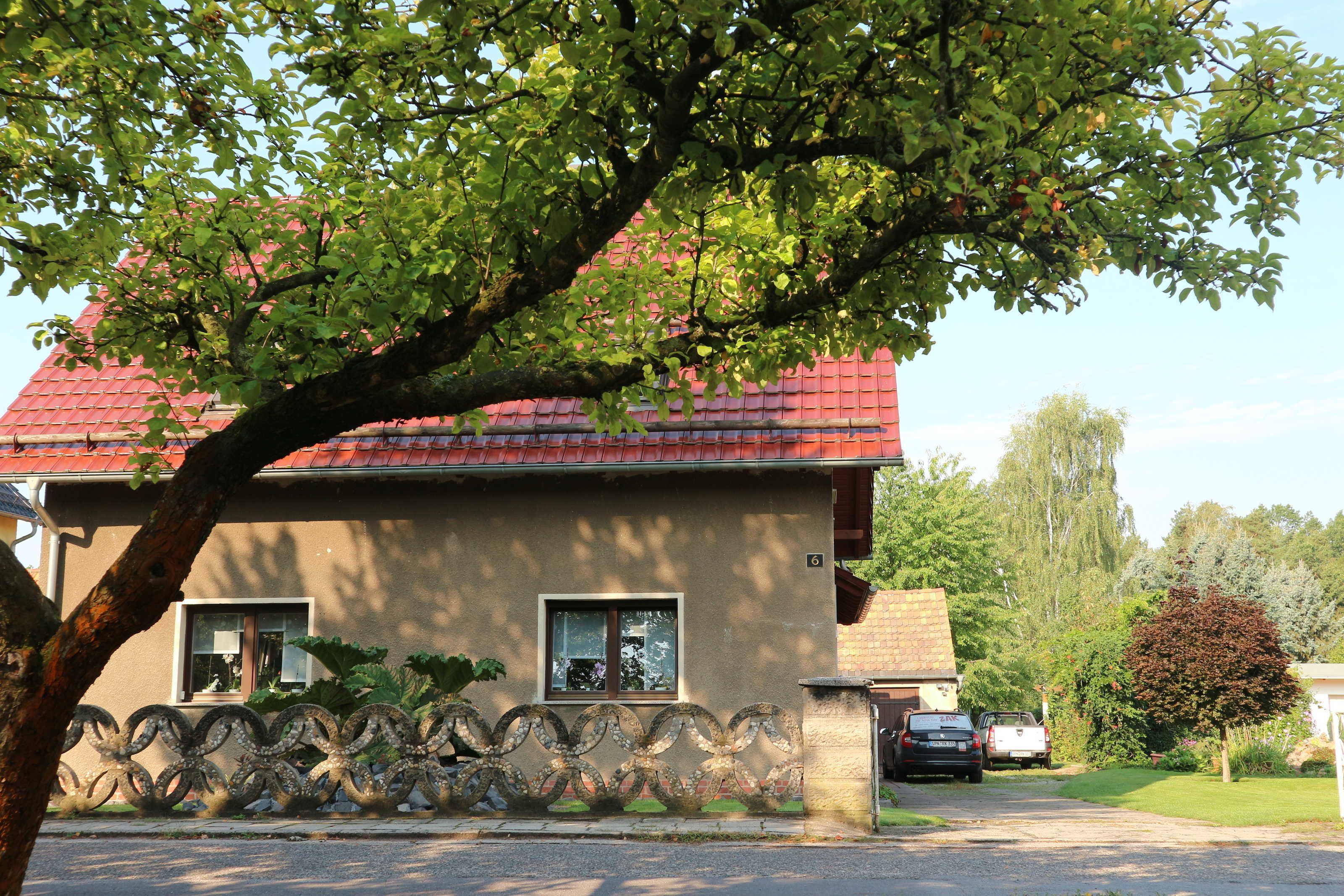 A house with a red roof, a window, and a tree in front.