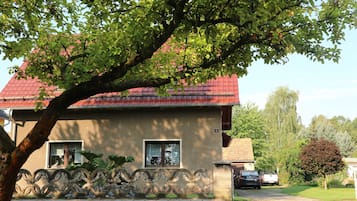 A house with a red roof, a window, and a tree in front.