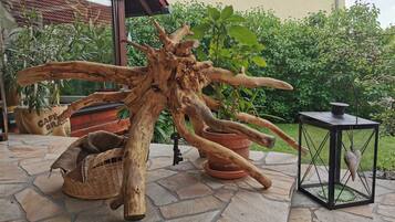 Une terrasse en pierre agrémentée d’une sculpture en bois rustique, de plantes en pot et d’une lanterne.