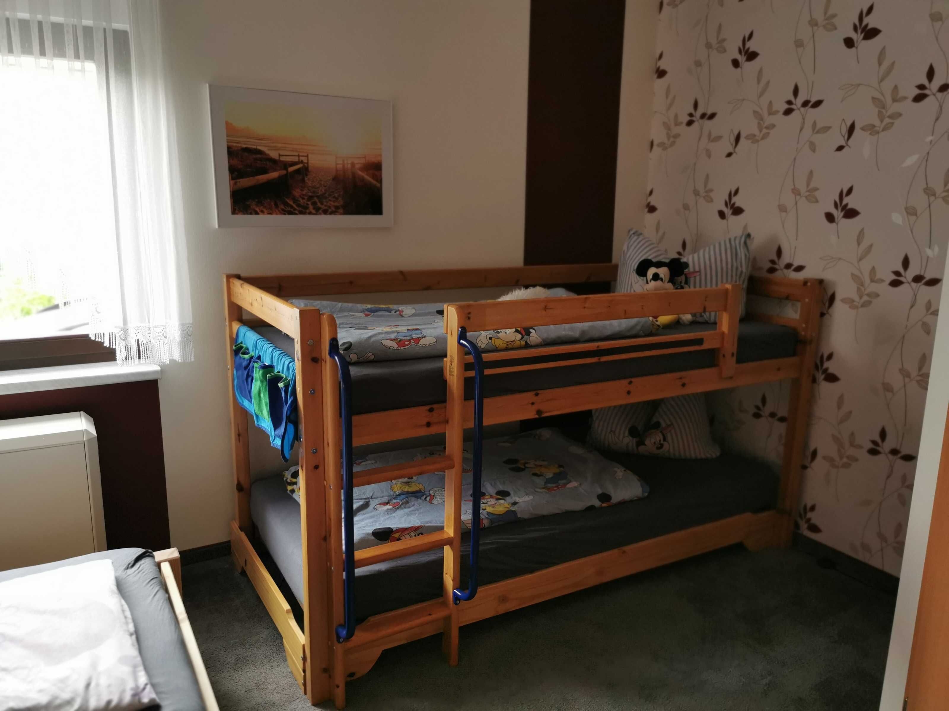 Ein Stockbett mit Fenster, Heizkörper und einer Wand mit Blumenmuster.