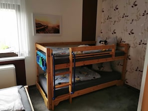Ein Stockbett mit Fenster, Heizkörper und einer Wand mit Blumenmuster.