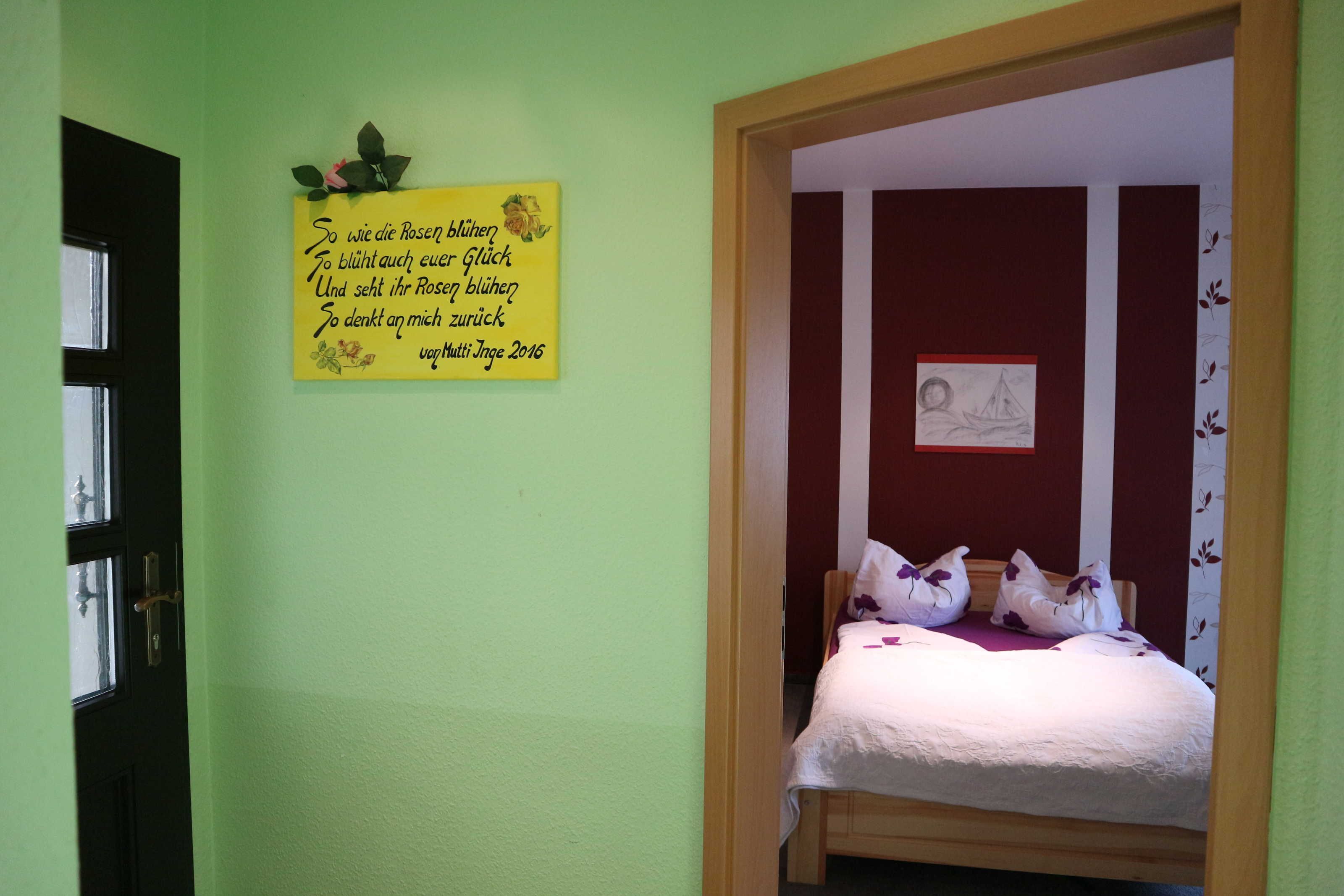 A room with a bed, a door, and a wall with a yellow sign.