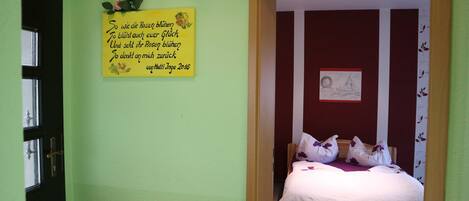A room with a bed, a door, and a wall with a yellow sign.