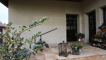 A stone patio with potted plants, a lantern, and a door leading to a building.