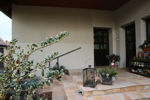 Un patio de piedra con plantas en macetas, un farol y una puerta que da a un edificio.