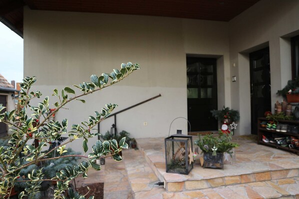 A stone patio with potted plants, a lantern, and a door leading to a building. - Vacation apartment Big Mama's Home - Big Mama's Home (Tschernitz)