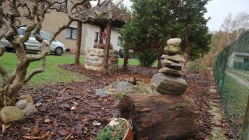 A garden with a stone structure, a wooden log, and a metal fence.