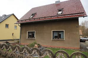 Ein Haus mit rotem Ziegeldach, zwei Fenstern und einer kleinen Veranda.