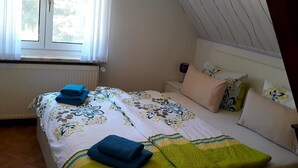 Un dormitorio con cama, almohadas y una ventana.