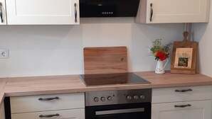 Una cocina moderna con armarios blancos, una campana extractora negra, una encimera de madera y un horno empotrado.