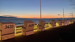 Eine Reihe nummerierter Liegestühle entlang einer Uferpromenade bei Sonnenuntergang.