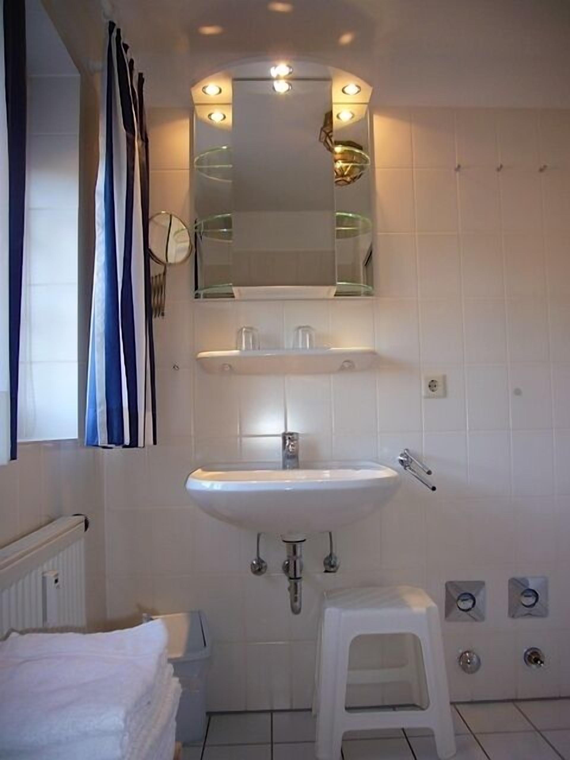 A bathroom with a white sink, mirror, and towel stack.
