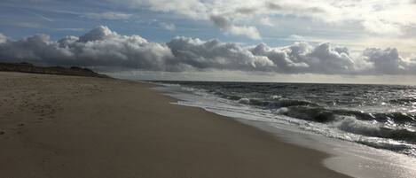 A beach with a wide sandy shore and waves approaching the beach.