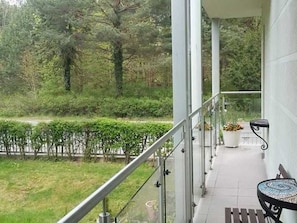 A balcony with a metal railing, a potted plant, and a table with a chair. - Apartment Bernstein (Swinoujscie)