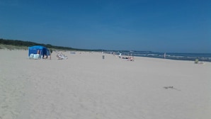 Una playa con una carpa azul y sillas de playa.