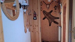 Un intérieur en bois agrémenté d’un miroir, de luminaires fixés au mur, d’un meuble en bois et d’une porte donnant sur une autre pièce.