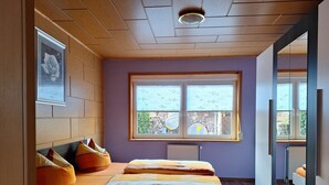 Une chambre à coucher avec un lit, des oreillers, une fenêtre et un radiateur.