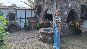 Un bâtiment rustique en pierre, doté d’une cheminée, de plantes en pot et d’une terrasse en bois.