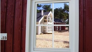 A window with a view of a building with a gabled roof and a red exterior. - House in the dunes (Mecklenburg Vorpommern)