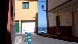 Eine schmale Straße mit einem Gebäude, das eine Garagentür und ein Schild mit der Aufschrift 'CALLE ANAGUA' zeigt.
