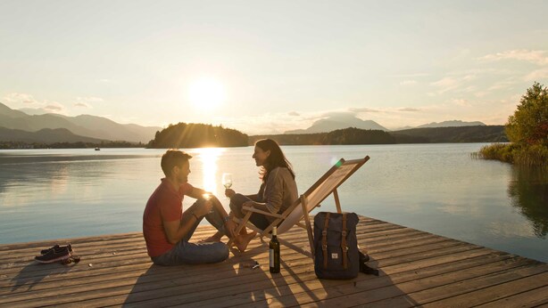 A couple sitting on a wooden dock by a lake at sunset. - Apartment of the SÜDsee 1 - Naturel Hoteldorf SEELEITN (Faak am See)