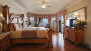 A spacious bedroom with a large bed, wooden furniture, a television, and a balcony with a view. - *** Luxurious Villa at River ***  (Florida)