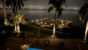 A nighttime view of a pool area with a dock and lounge chairs, overlooking a calm body of water. - *** Luxurious Villa at River ***  (Florida)