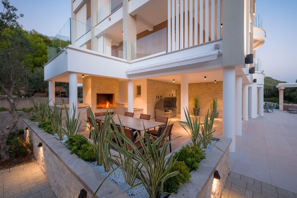 A modern house with a dining area, outdoor seating, and a fireplace.