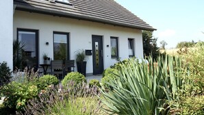 A modern two-story house with a flat roof, large windows, and a well-maintained garden with various plants. - House at the sea (Wohlenberg)